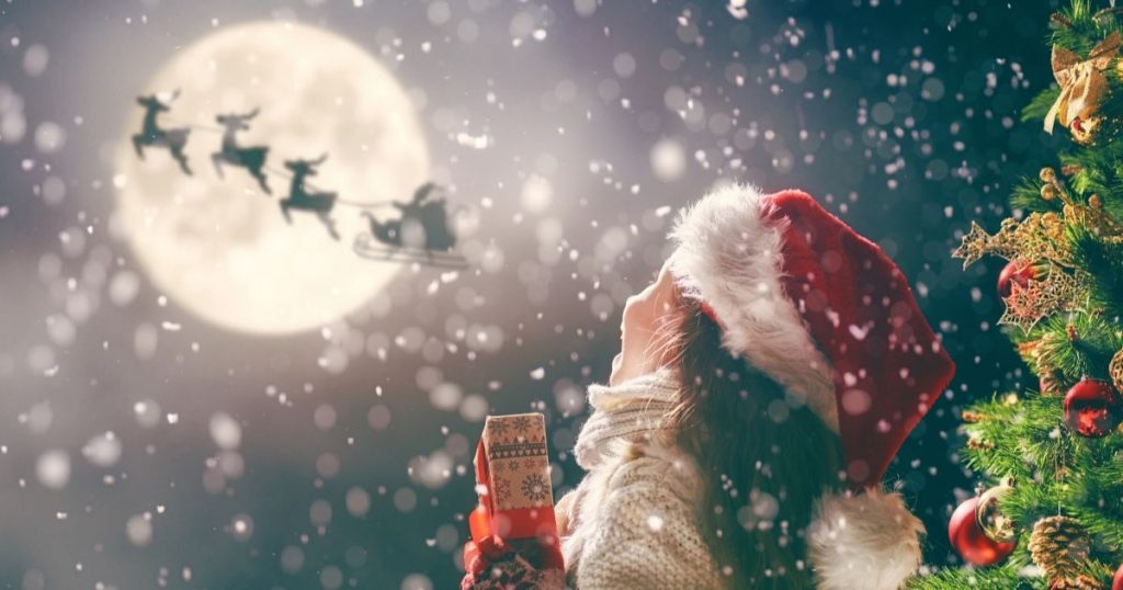 Fillette avec un cadeau qui admire le traîneau du père Noël dans le ciel - Comment réinventer la rencontre avec le père Noël - Audace